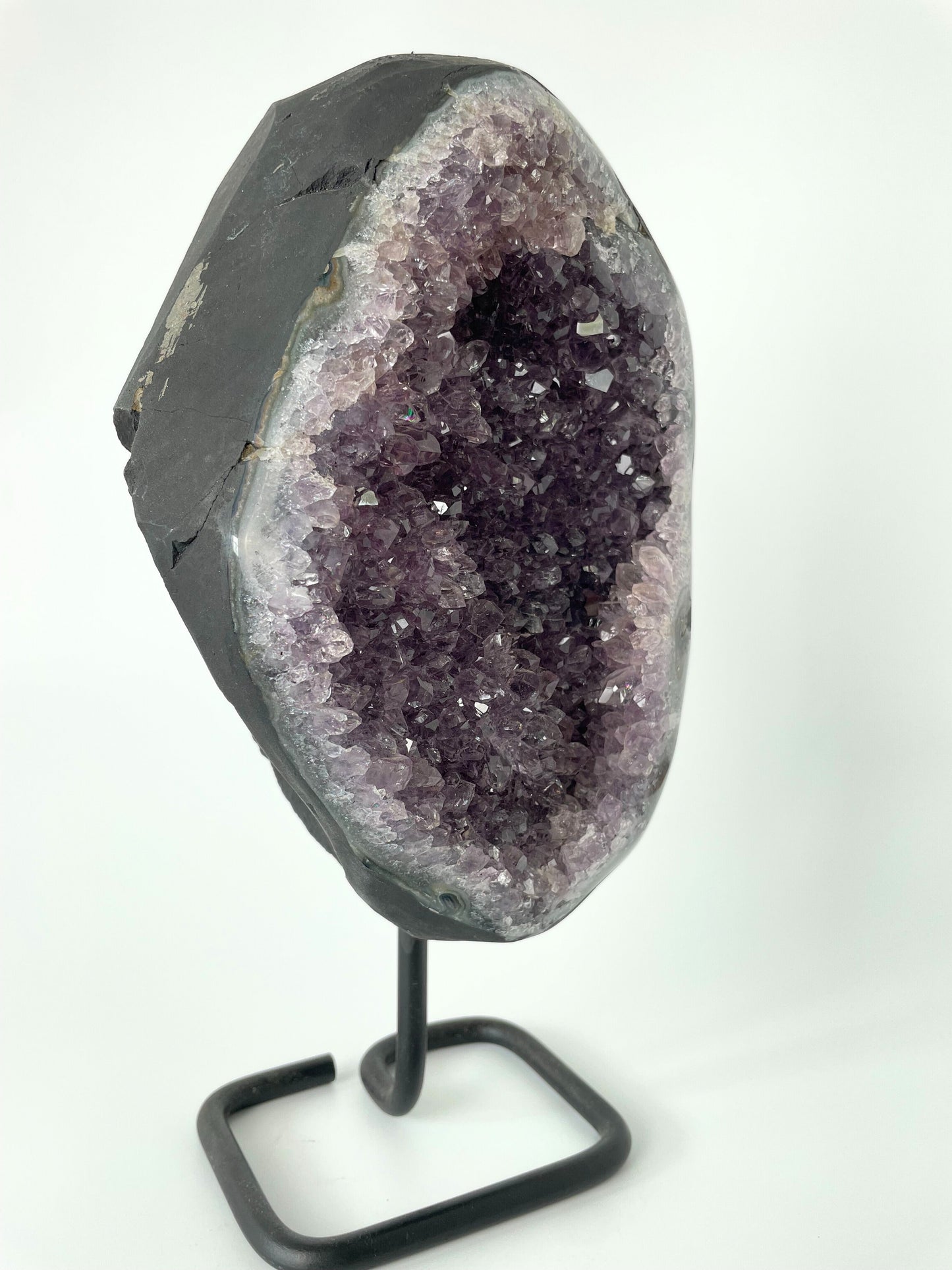 Image of a gleaming amethyst cluster displayed on a stand, showcasing its vibrant purple hues and natural crystal formations.