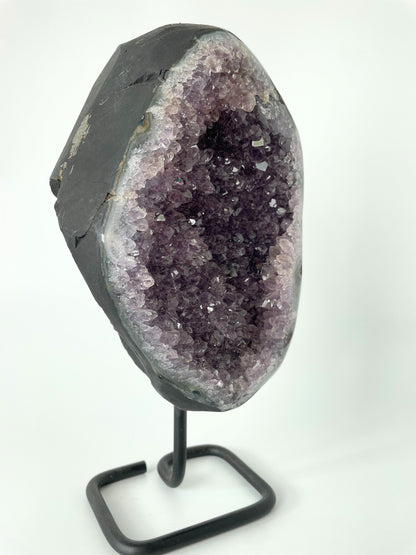 Image of a gleaming amethyst cluster displayed on a stand, showcasing its vibrant purple hues and natural crystal formations.