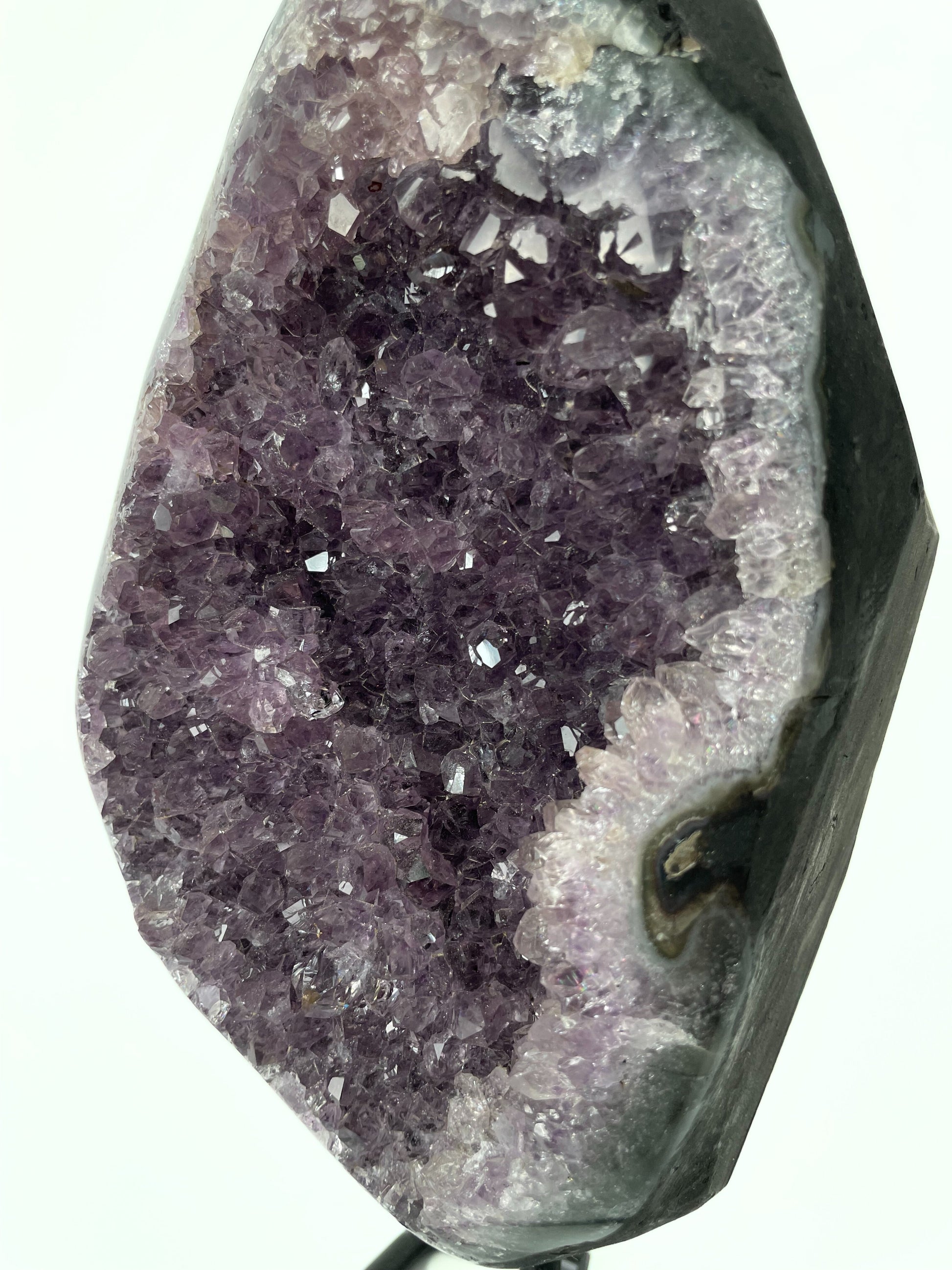 Image of a gleaming amethyst cluster displayed on a stand, showcasing its vibrant purple hues and natural crystal formations.